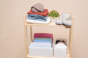 Wardrobe rack with clothes and storage box on the shelves on light background with copy space.
