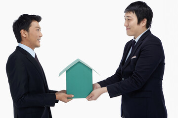 Two businessmen holding a cardboard house