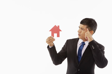 Businessman holding up a cut out house, contemplating