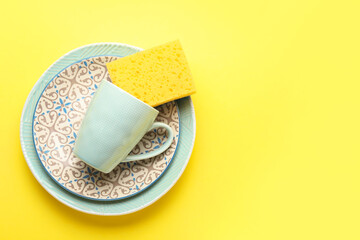 Clean dishes and sponge on color background