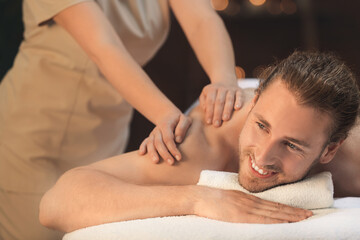 Fototapeta na wymiar Handsome young man receiving massage in spa salon