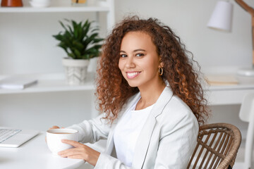 Beautiful young African-American woman drinking hot tea at home