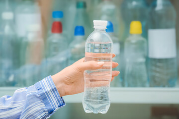Woman taking bottle of water from fridge in shop