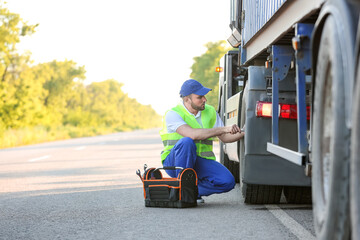 Male driver fixing big truck outdoors