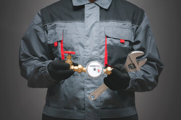Plumber is holding in hands a water meter and adjustable wrench close up.