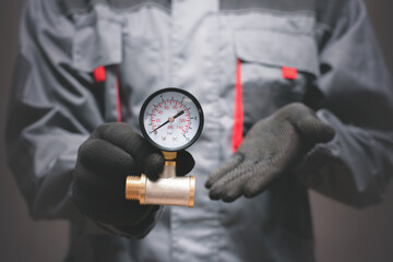 Plumber is holding a water pressure meter close up.