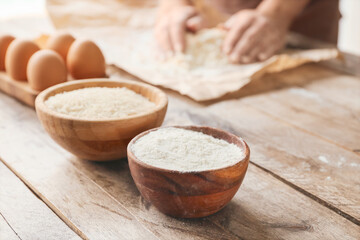 Bowls with raw rice and flour on table