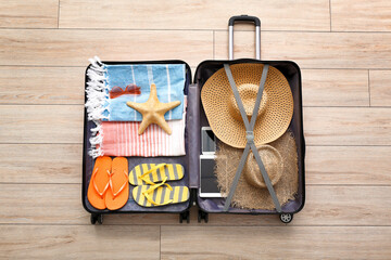 Packed suitcase with beach accessories on wooden background. Travel concept