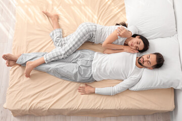 Young couple sleeping in bed, top view