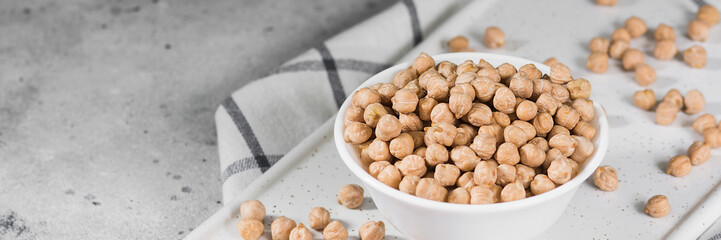 Chickpeas in a white bowl on the light gray kitchen table. Chickpeas in a plate close-up. Banner with space for text
