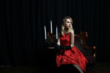 young and beautiful girl in a red dress and a candelabrum with candles