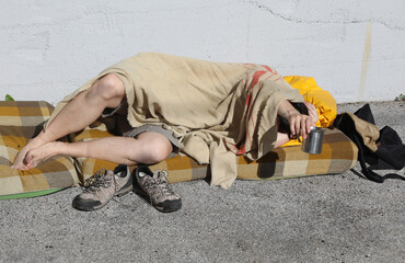 homeless man begging passersby in a city street while resting un