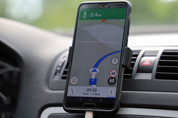 smartphone with navigator map on dashboard in a car, close up of navigation with an gps app