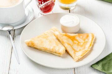 Breakfast pancakes with sour cream on a white, round plate