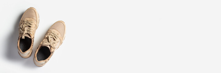 Women's beige sneakers with laces on a light background. Flat lay, top view. Banner