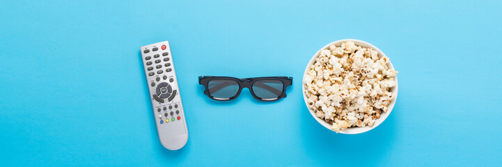 Bowl with popcorn, Imax glasses, remote control for TV on a blue