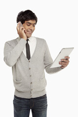 Man talking on the phone while looking at digital tablet