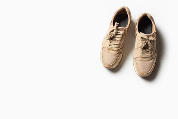 Women's beige sneakers with laces on a light background. Flat lay, top view