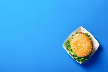 Fresh burger on a bright blue background. Flat lay, top view