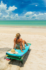 Woman on a sun lounger at the white sand tropical beach