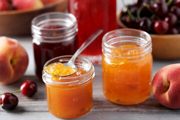 Fototapeta na wymiar Variety of jams or preserves in glass jars. Strawberry, cherry and peach marmalade. Homemade dessert