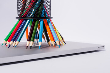 colored pencils in pencil holder on modern laptop on white background