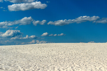 desert of white sand under an open sky with clouds