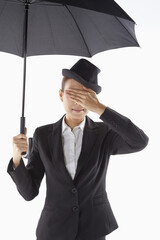 Businesswoman covering her eyes while standing under the umbrella