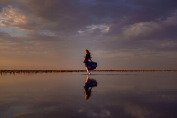 Elegant woman in silky dress walking by a salt lake.