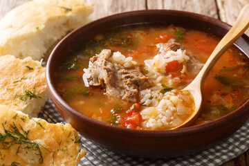 Spicy Georgian kharcho soup in a bowl served with Georgian bread close-up on the table. horizontal