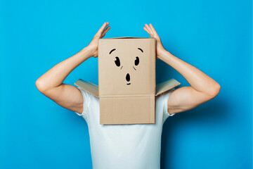 Young man in a white T-shirt with a cardboard box on his head ma