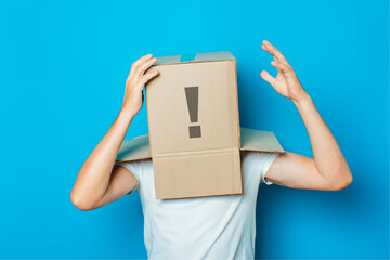 Young man in a white T-shirt with a cardboard box on his head ma
