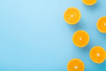 Bright halves of oranges. Fresh fruits. Empty place for text on light blue table background. Pastel color. Closeup. Top down view.