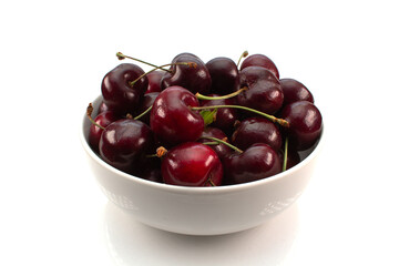 A bowl of black cherries on a white background