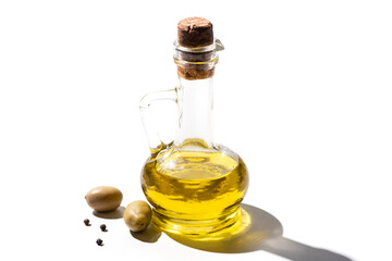 olive oil in jar near green olives and black pepper on white background