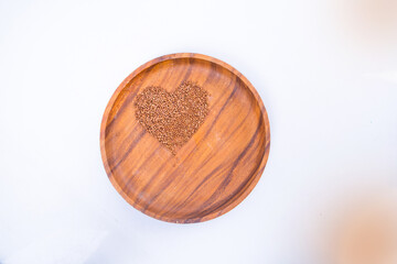 Theme of diet and weight loss on a white background. buckwheat in a wooden plate is laid out in the shape of a heart.