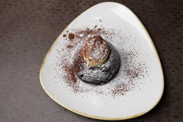 Chocolate cake with white powder on a white plate. dessert close-up, top view