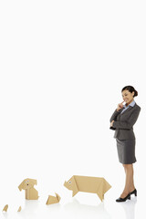 Businesswoman looking over paper animals, contemplating