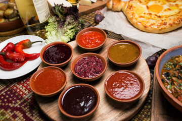 spicy sauces in round plates. cheese and vegetables around. close-up, top view. Georgian national cuisine