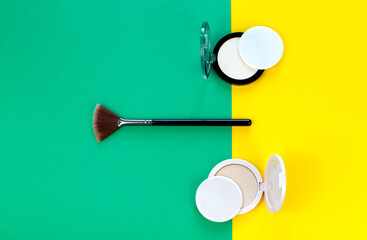 Makeup: powder and cosmetic brush on a bright yellow and green background.
