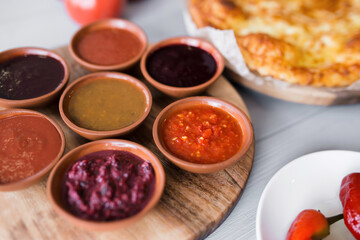spicy sauces in round plates. cheese and vegetables around. close-up, top view. Georgian national cuisine