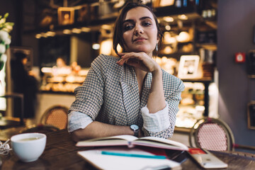 Smiling young female student with planner in cafe