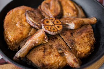 Grilled meat. Baked chicken in a pan close-up. Gray wooden background, spicy sauces and cutlery. Georgian cuisine