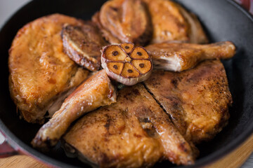 Grilled meat. Baked chicken in a pan close-up. Gray wooden background, spicy sauces and cutlery. Georgian cuisine