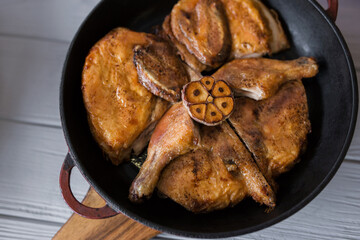 Grilled meat. Baked chicken in a pan close-up. Gray wooden background, spicy sauces and cutlery. Georgian cuisine