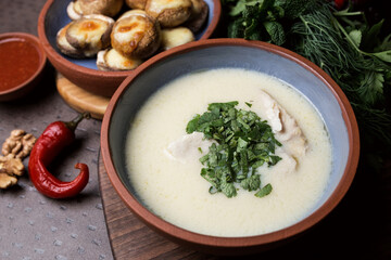 Cream soup with meat and parsley. Plate with baked mushrooms. Chili pepper and walnut. Georgian cuisine