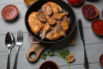 Grilled meat. Baked chicken in a pan close-up. Gray wooden background, spicy sauces and cutlery. Georgian cuisine