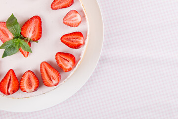 Cheesecake with strawberries and mint, on a table with a light tablecloth. Sweet homemade breakfast. Copy space.
