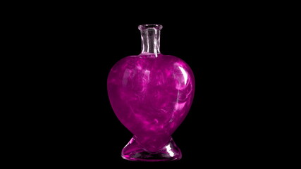 Glass bottle in the form of a heart with pink liquid. The elixir is spinning and overflowing with liquid. Potion of love is isolated on a black background.