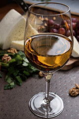 A glass of white wine close-up. Cheese and vegetables are sliced ​​on a board in the background. Georgian cuisine